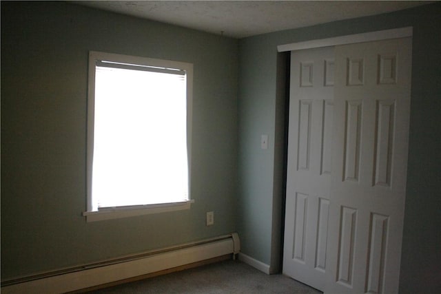 unfurnished bedroom with a closet and a baseboard heating unit