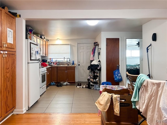 kitchen featuring light tile patterned flooring, white appliances, and sink