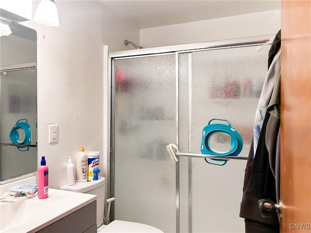 bathroom featuring toilet, a stall shower, and vanity