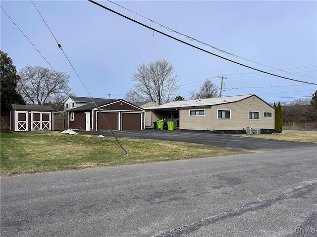 view of front facade with fence, a front yard, a garage, an outbuilding, and driveway