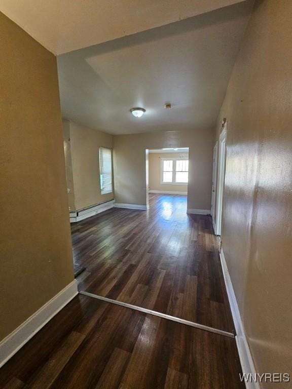 unfurnished room featuring dark hardwood / wood-style floors and a baseboard heating unit