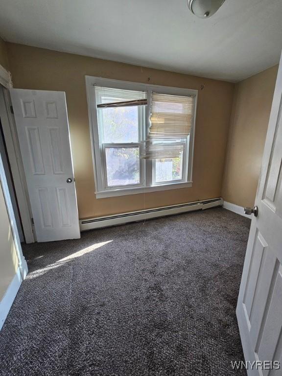 carpeted empty room featuring a baseboard radiator