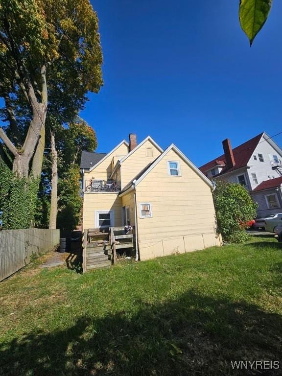 view of side of home featuring a yard and a balcony