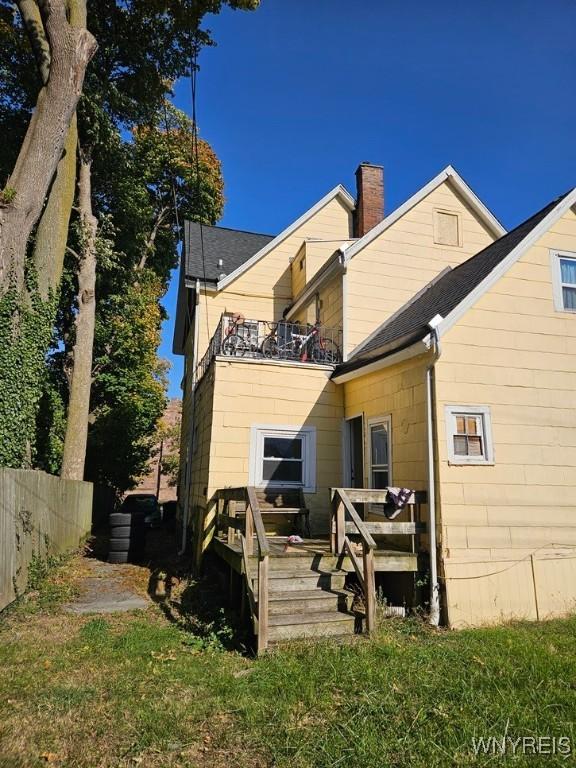 rear view of house featuring a yard, a balcony, and a wooden deck