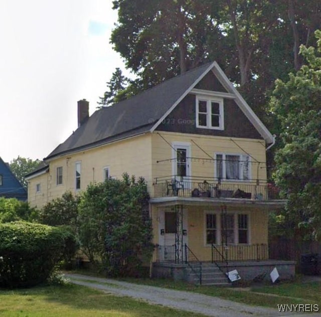 view of front of house featuring a porch, a balcony, and a front lawn