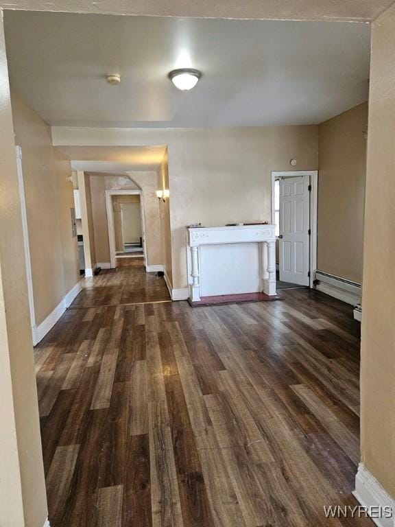 unfurnished living room with dark hardwood / wood-style flooring and baseboard heating