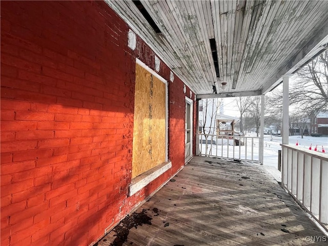 snow covered deck featuring covered porch