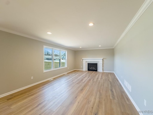 unfurnished living room with visible vents, ornamental molding, light wood-style floors, a fireplace, and baseboards