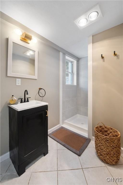 bathroom with tile patterned flooring, a tile shower, and vanity