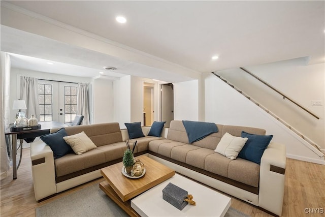 living room featuring french doors, light wood-type flooring, and ornamental molding