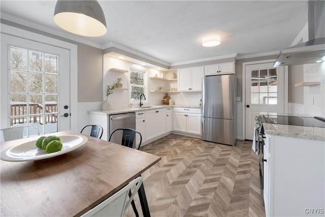 kitchen featuring exhaust hood, white cabinets, appliances with stainless steel finishes, light stone counters, and light parquet flooring