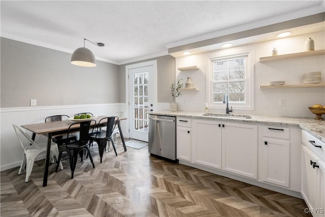 kitchen with light stone counters, stainless steel dishwasher, sink, pendant lighting, and white cabinetry