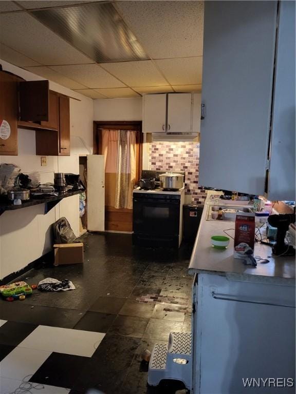 kitchen with white range with gas stovetop, decorative backsplash, white cabinetry, and a drop ceiling