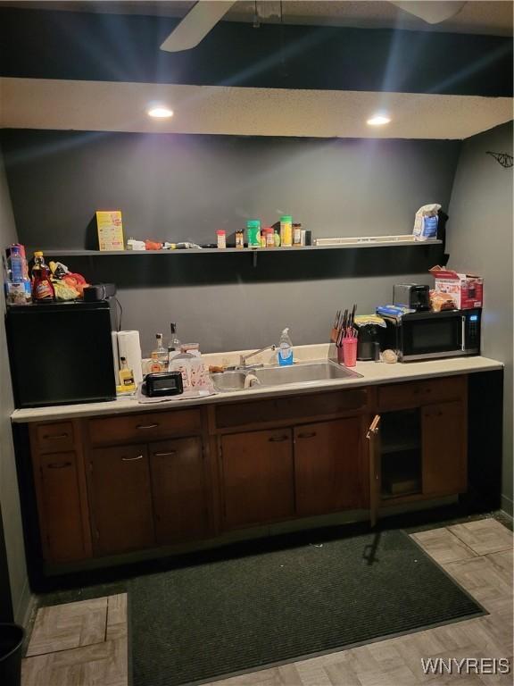 bar with dark brown cabinets, ceiling fan, and sink