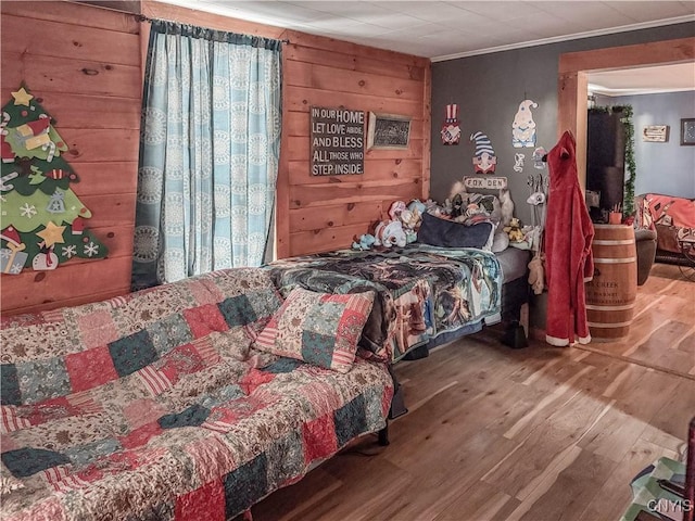 bedroom featuring wooden walls, hardwood / wood-style floors, and ornamental molding