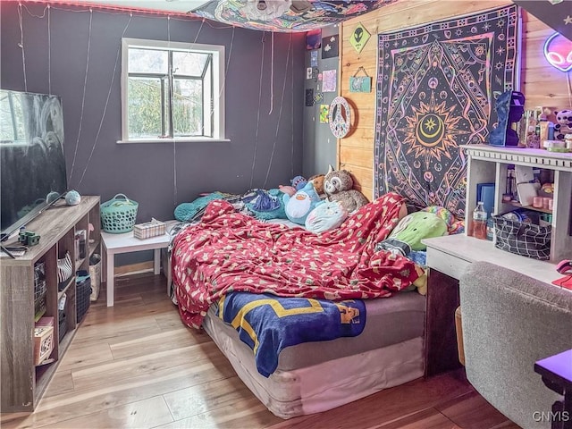 bedroom with hardwood / wood-style floors and wood walls