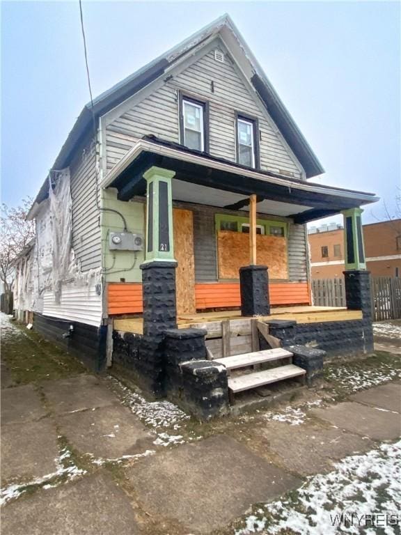 snow covered back of property with a porch