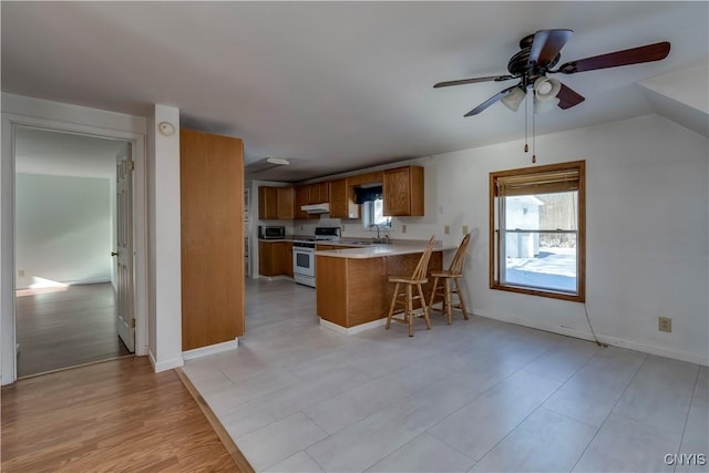 kitchen featuring ceiling fan, white range, kitchen peninsula, and sink