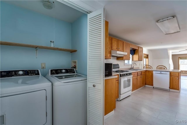 interior space featuring kitchen peninsula, white appliances, ceiling fan, sink, and independent washer and dryer