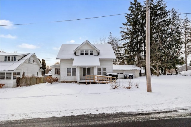 snow covered house with a garage, an outdoor structure, and a wooden deck