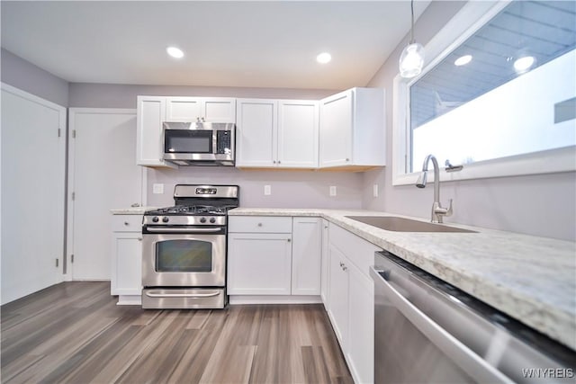 kitchen with dark wood-type flooring, hanging light fixtures, stainless steel appliances, white cabinetry, and sink