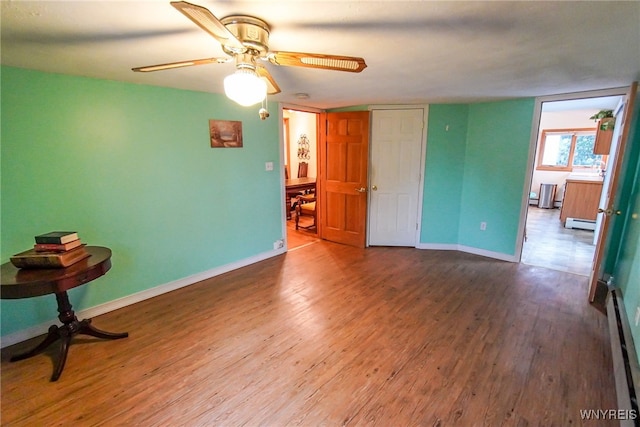 empty room featuring hardwood / wood-style flooring, a baseboard radiator, and ceiling fan