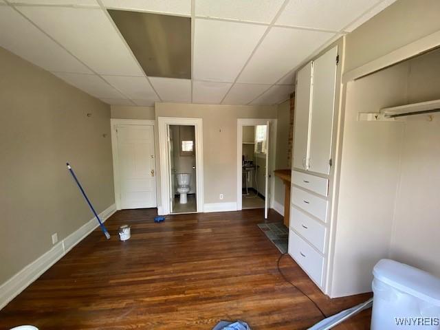 interior space with ensuite bath, dark hardwood / wood-style flooring, and a drop ceiling