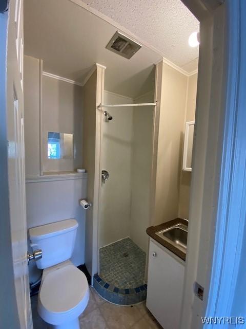 bathroom with a shower, crown molding, a textured ceiling, toilet, and vanity