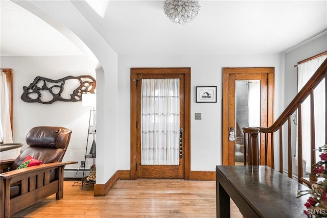 foyer entrance featuring baseboard heating and light hardwood / wood-style floors