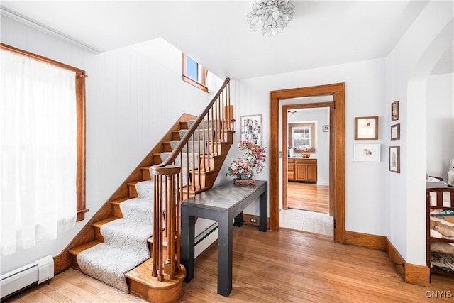 staircase featuring wood-type flooring and a baseboard heating unit