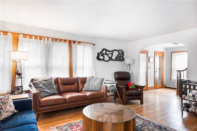 living room with light hardwood / wood-style floors, a textured ceiling, and a baseboard heating unit