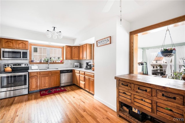 kitchen featuring sink, backsplash, a chandelier, light hardwood / wood-style floors, and stainless steel appliances