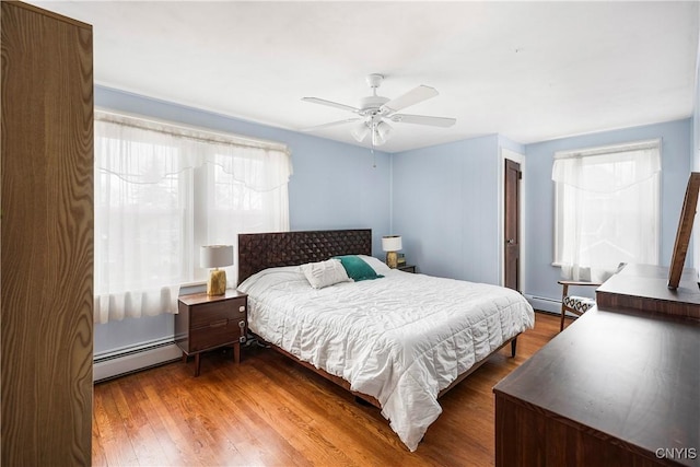 bedroom with baseboard heating, ceiling fan, and dark hardwood / wood-style flooring