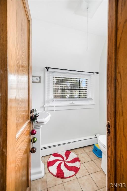 bathroom with tile patterned flooring, a baseboard heating unit, sink, and toilet