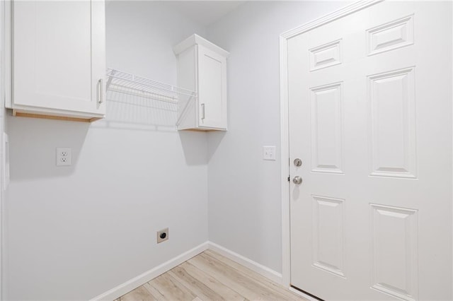 washroom with hookup for an electric dryer, light wood-type flooring, and cabinets