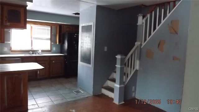 kitchen featuring black refrigerator, light tile patterned floors, dishwasher, and sink