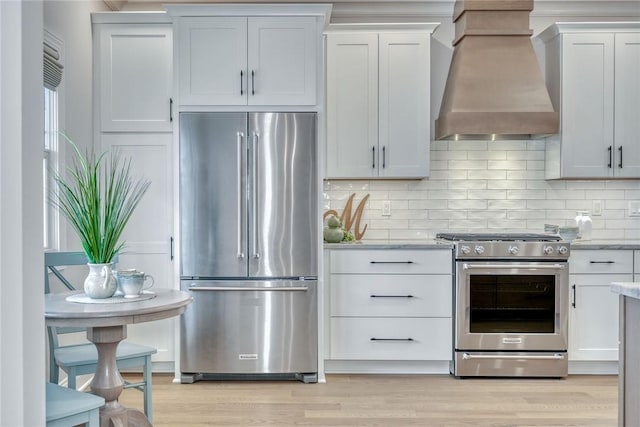 kitchen with white cabinetry, backsplash, custom exhaust hood, and stainless steel appliances