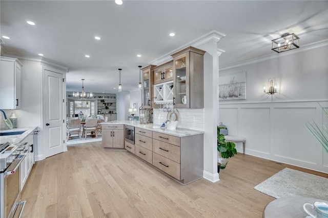 kitchen featuring sink, appliances with stainless steel finishes, light stone countertops, decorative light fixtures, and light wood-type flooring