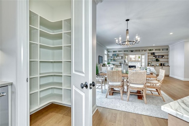 dining room featuring crown molding, light hardwood / wood-style flooring, and a chandelier