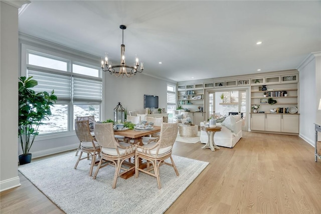 dining space with crown molding, a notable chandelier, light hardwood / wood-style floors, and built in shelves