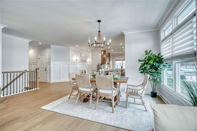 dining space featuring ornamental molding, light hardwood / wood-style floors, and a notable chandelier