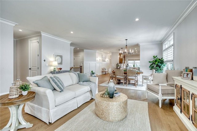 living room featuring crown molding, a notable chandelier, and light hardwood / wood-style flooring