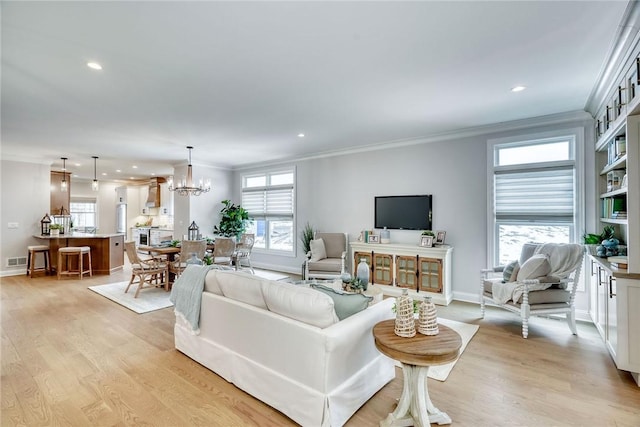 living room with an inviting chandelier, ornamental molding, light hardwood / wood-style floors, and a wealth of natural light