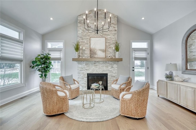 sitting room with a healthy amount of sunlight, a fireplace, a chandelier, and light wood-type flooring