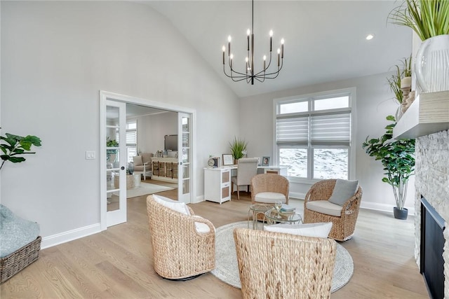 living room with french doors, a stone fireplace, an inviting chandelier, high vaulted ceiling, and light hardwood / wood-style floors