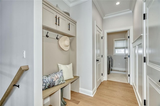 mudroom featuring ornamental molding, washer and dryer, and light wood-type flooring