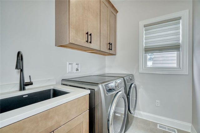 laundry area with cabinets, tile patterned floors, sink, and washing machine and dryer