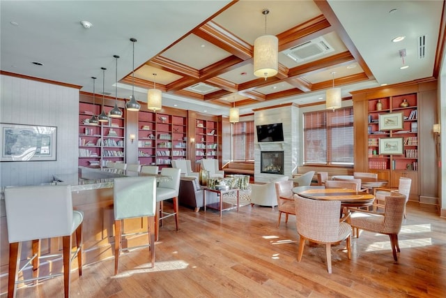 dining room with coffered ceiling, light hardwood / wood-style flooring, a large fireplace, wooden walls, and beamed ceiling