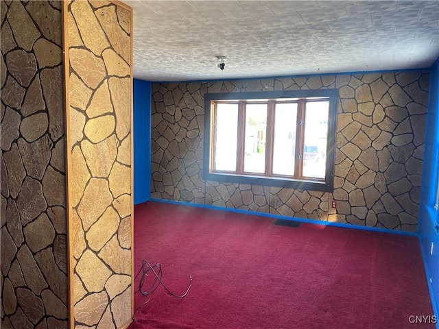 unfurnished room with carpet flooring and a textured ceiling