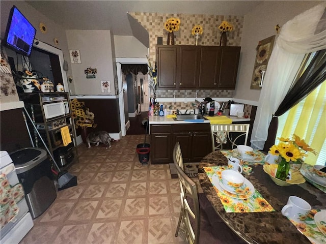 kitchen featuring decorative backsplash, dark brown cabinets, and sink